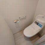 ホワイトを基調とした明るく清潔感のある空間に設置されたトイレ。今回のリフォームで温水洗浄便座が付いたものに新規交換。(内装)