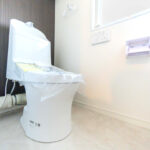 白を基調とした空間に設置されたトイレ。温水洗浄便座のついたものを新規に交換。(内装)
