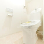 ホワイトを基調とした明るく清潔感のある空間に設置されたトイレ。温水洗浄便座のついたものに交換されさらに清潔感を増しています。(内装)