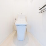 ホワイトを基調とした明るく清潔感のある空間に設置されたトイレ。温水洗浄便座のついたものに交換されさらに清潔感を増しています。(内装)