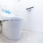 白を基調とした清潔感のある空間に設置をされたトイレ。温水洗浄便座のついたものに交換し、さらに清潔感は増している。(内装)