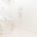 清潔感溢れるホワイトを基調とした空間に設置されたトイレ。温水洗浄便座が付いたものに交換してさらに清潔感が増しました。(内装)